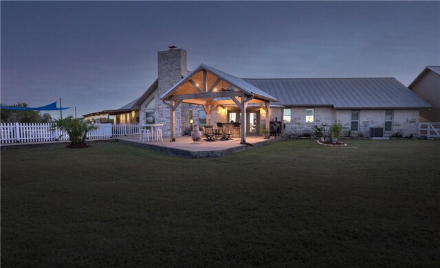 back house at dusk featuring cooling unit, a yard, and a patio