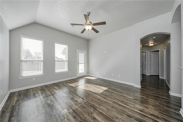 unfurnished room with dark wood-style floors, visible vents, baseboards, arched walkways, and vaulted ceiling