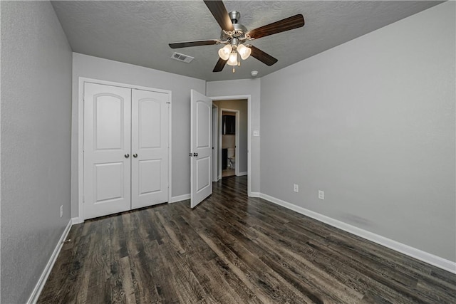 unfurnished bedroom featuring dark wood-style floors, visible vents, a textured ceiling, and baseboards