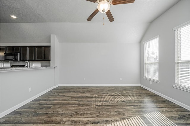 interior space with baseboards, lofted ceiling, ceiling fan, and dark wood-style flooring