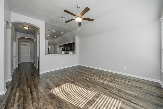 unfurnished living room with visible vents, dark wood-type flooring, baseboards, vaulted ceiling, and arched walkways