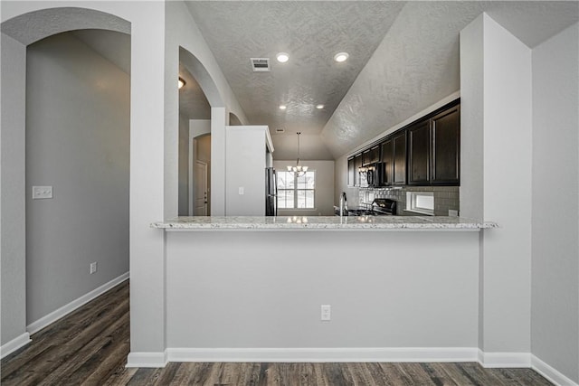 kitchen featuring backsplash, range with gas cooktop, an inviting chandelier, and dark wood-style flooring