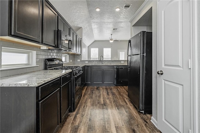 kitchen with tasteful backsplash, dark wood finished floors, light stone counters, black appliances, and a sink