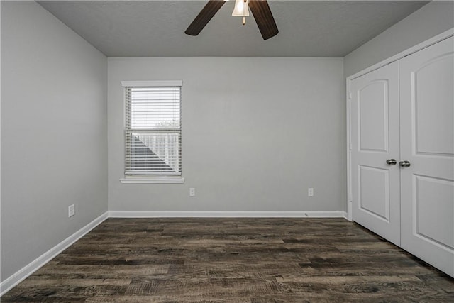 unfurnished bedroom with a ceiling fan, baseboards, dark wood-style flooring, a closet, and a textured ceiling