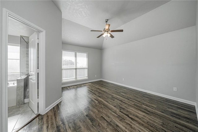 empty room with a ceiling fan, lofted ceiling, wood finished floors, and baseboards