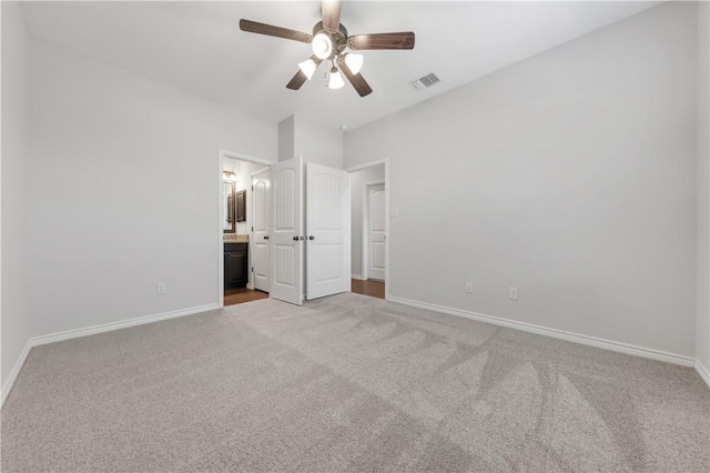 unfurnished bedroom featuring visible vents, connected bathroom, baseboards, carpet floors, and a ceiling fan