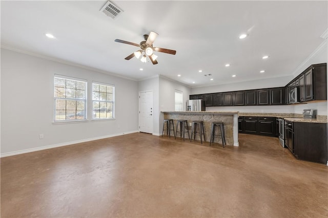 kitchen featuring finished concrete floors, stainless steel appliances, a kitchen bar, and baseboards