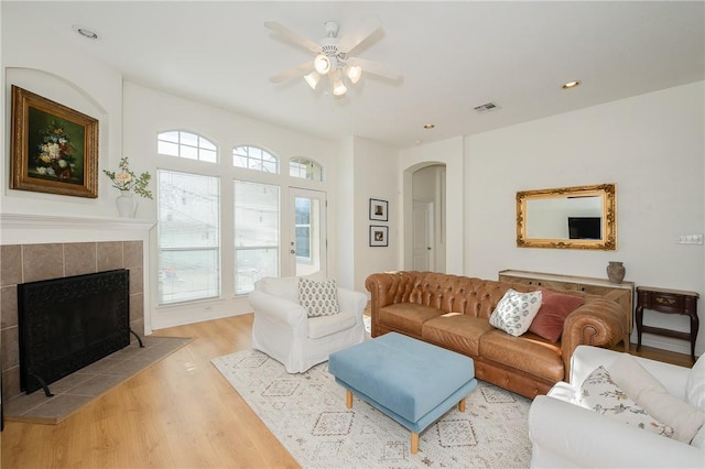 living room featuring a fireplace, light hardwood / wood-style floors, and ceiling fan