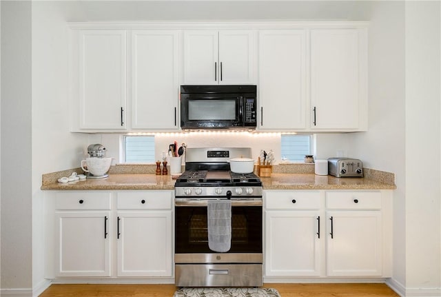 kitchen with light stone counters, stainless steel range with gas cooktop, and white cabinets