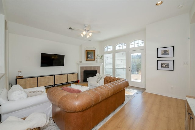 living room with ceiling fan, a wealth of natural light, a fireplace, and light hardwood / wood-style floors