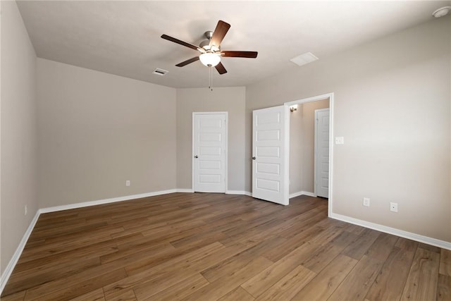 unfurnished bedroom with ceiling fan and dark wood-type flooring