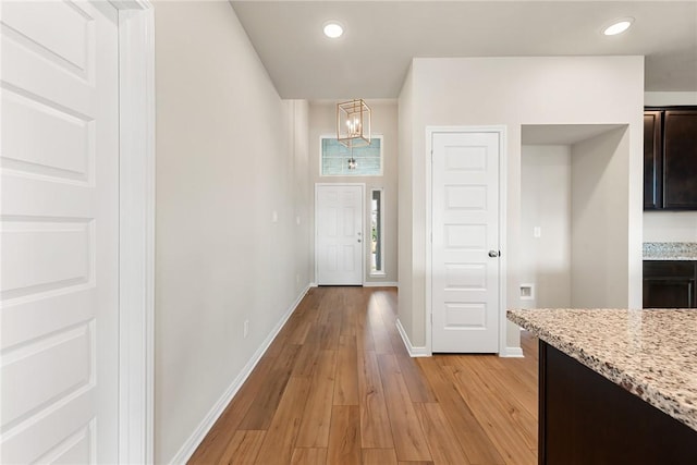 hall with light hardwood / wood-style floors and a notable chandelier