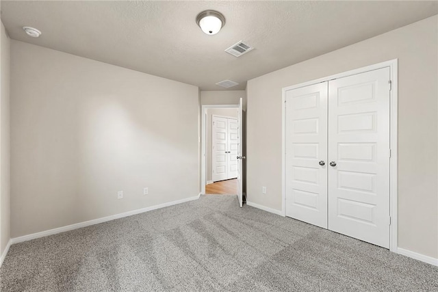 unfurnished bedroom with a closet, light colored carpet, and a textured ceiling