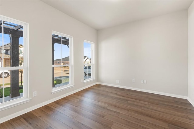 spare room with dark hardwood / wood-style flooring and a wealth of natural light