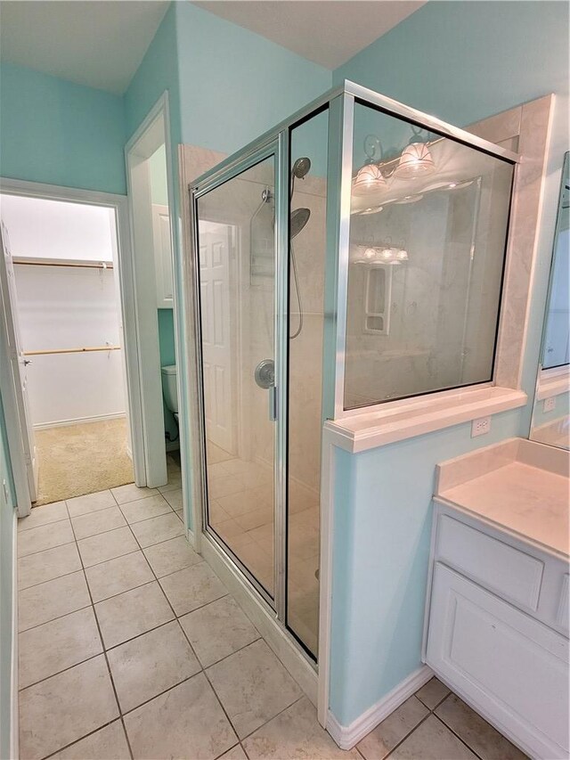 bathroom with tile patterned flooring, vanity, toilet, and a shower with door