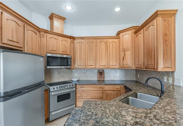 kitchen featuring backsplash, sink, dark stone counters, and stainless steel appliances