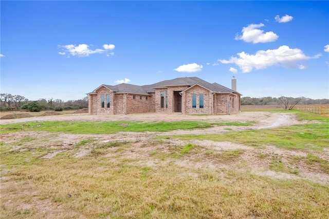 view of front of property with a rural view and a front lawn