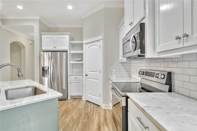 2124 Mountain Wind Loop, Bryan, TX 77807 - kitchen featuring appliances with stainless steel finishes, light wood-style floors, crown molding, white cabinetry, and tasteful backsplash