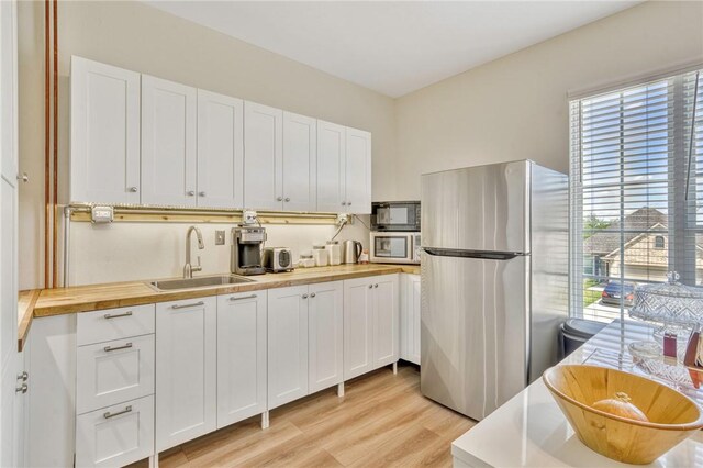 2124 Mountain Wind Loop, Bryan, TX 77807 - kitchen with stainless steel appliances, plenty of natural light, light wood-style floors, and white cabinets