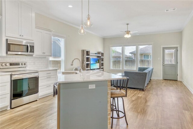 2124 Mountain Wind Loop, Bryan, TX 77807 - kitchen featuring stainless steel appliances, ceiling fan, decorative backsplash, open floor plan, and a breakfast bar