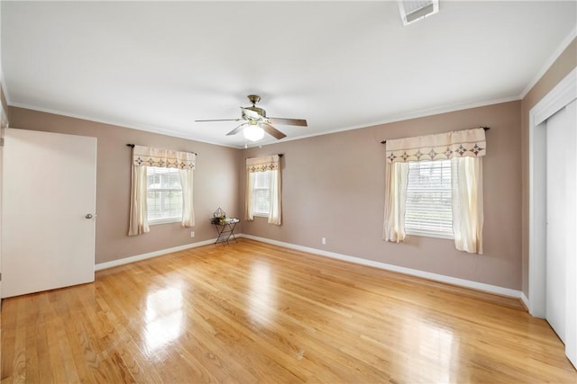 empty room with light hardwood / wood-style flooring, a wealth of natural light, and crown molding