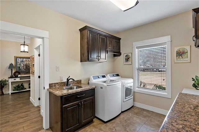 washroom with a sink, separate washer and dryer, baseboards, and cabinet space