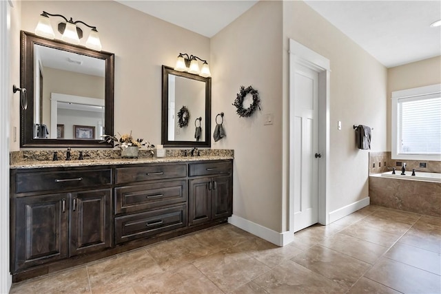 full bathroom featuring baseboards, a sink, a garden tub, and double vanity