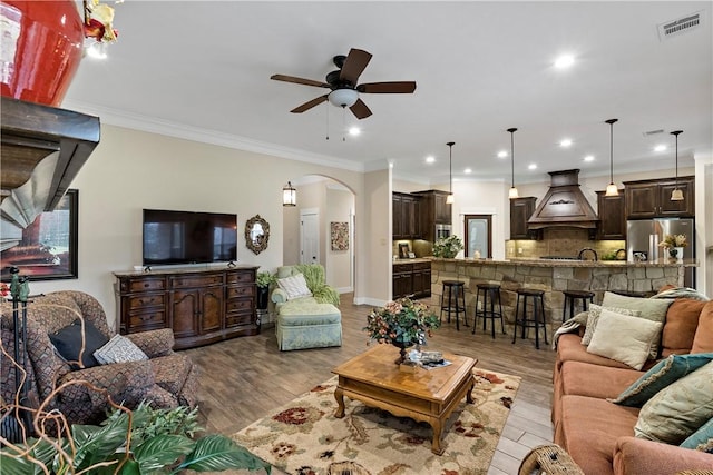 living area with arched walkways, ceiling fan, recessed lighting, and visible vents