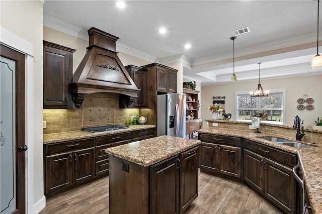 kitchen featuring visible vents, wood finished floors, custom range hood, a sink, and stainless steel appliances
