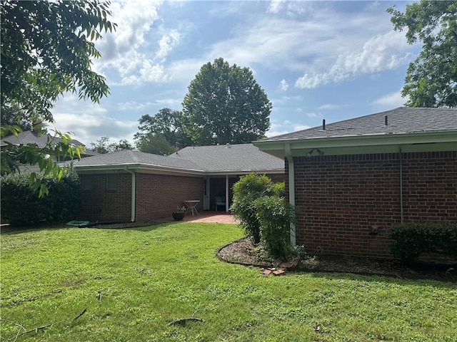 604 W Buck St, Caldwell, TX 77836 - rear view of property featuring brick siding, a lawn, and a patio area