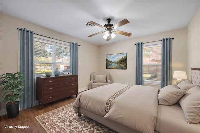 bedroom with ceiling fan, multiple windows, and dark hardwood / wood-style floors