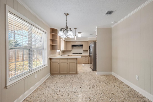 kitchen with ornamental molding, pendant lighting, stainless steel fridge, and sink