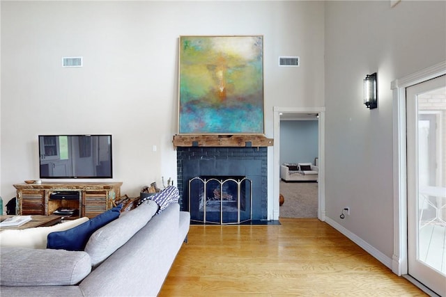 living room featuring light wood-type flooring and a towering ceiling