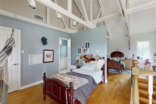 bedroom featuring hardwood / wood-style flooring, beamed ceiling, ensuite bath, and high vaulted ceiling