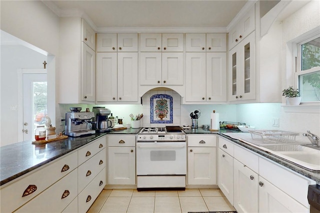 kitchen with white cabinets, white stove, backsplash, light tile patterned floors, and sink