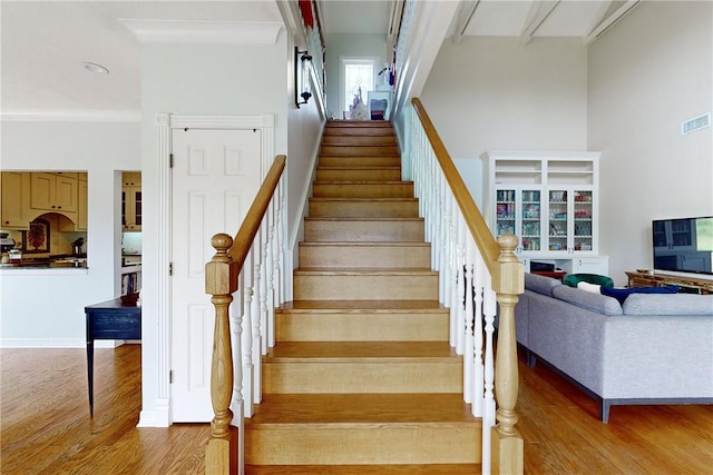 stairway with wood-type flooring and a towering ceiling