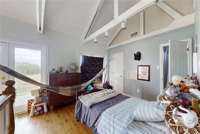 bedroom featuring light wood-type flooring, high vaulted ceiling, beamed ceiling, and rail lighting