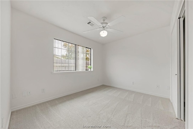 empty room featuring ceiling fan and light colored carpet