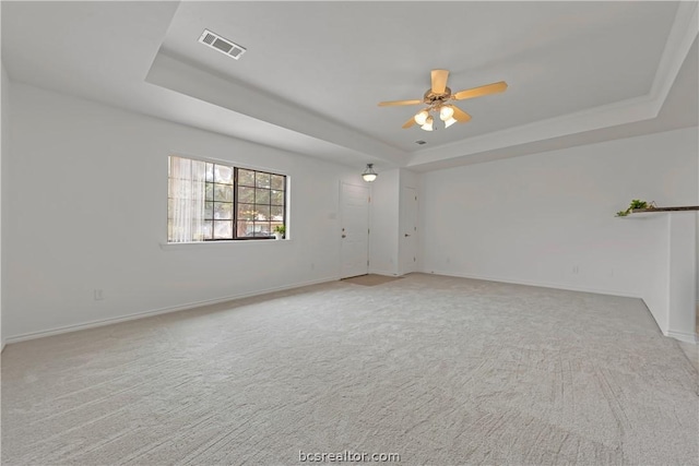 carpeted spare room with a raised ceiling and ceiling fan