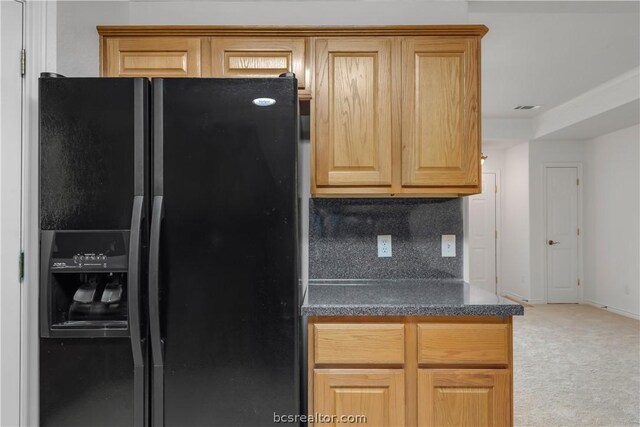 kitchen featuring decorative backsplash, black fridge, and carpet floors