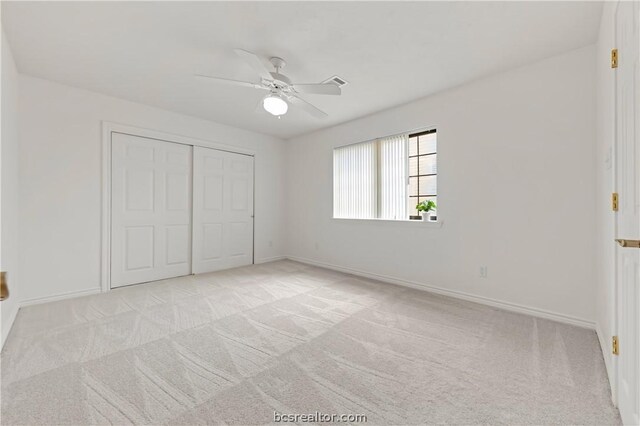 unfurnished bedroom featuring light carpet, a closet, and ceiling fan