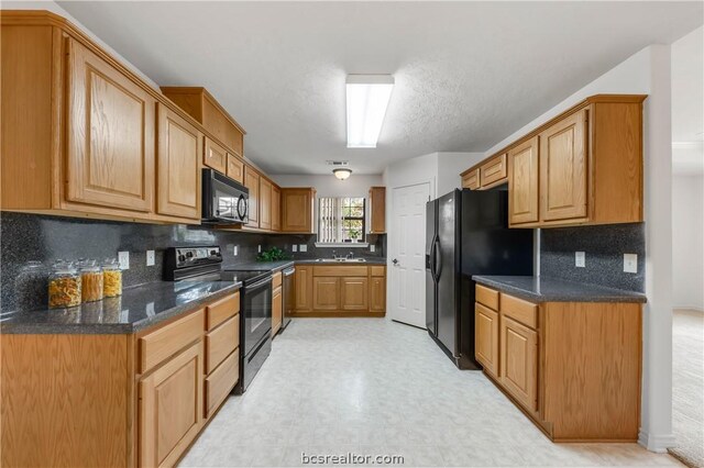 kitchen featuring black appliances, backsplash, dark stone countertops, and sink