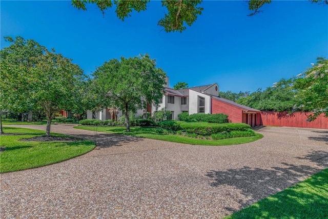 view of front of property featuring a garage, a front yard, gravel driveway, and fence