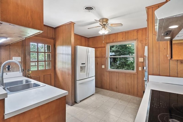 kitchen featuring a sink, brown cabinets, visible vents, under cabinet range hood, and white refrigerator with ice dispenser