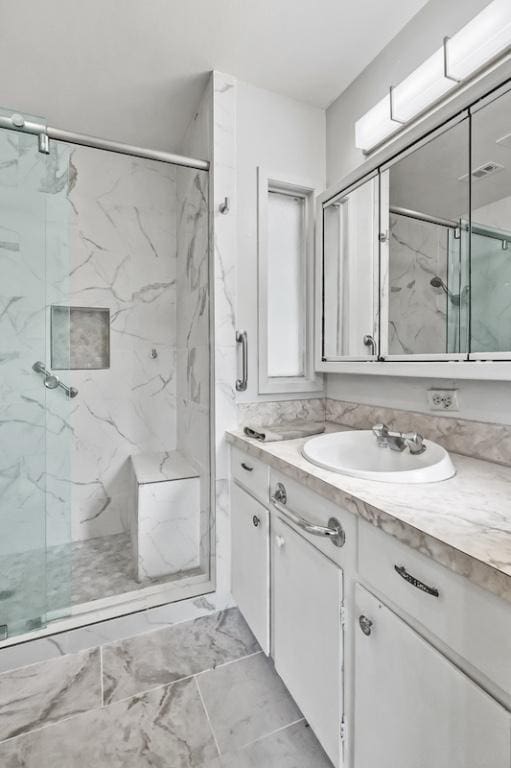 full bath with a marble finish shower, marble finish floor, vanity, and visible vents