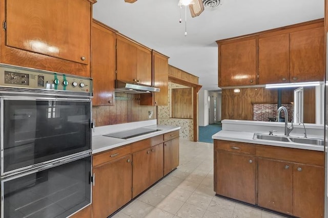 kitchen with black electric cooktop, a sink, light countertops, and under cabinet range hood