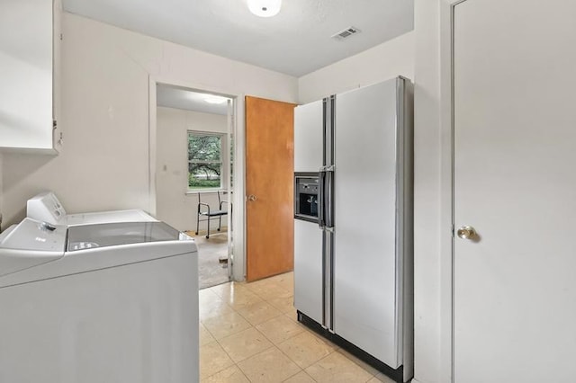 clothes washing area with washing machine and dryer, cabinet space, and visible vents