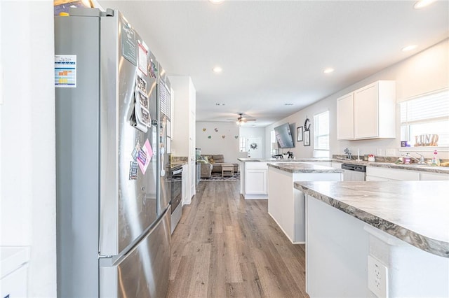 975 Harper Ln, Bryan, TX 77803 - kitchen featuring white cabinets, open floor plan, light wood-style floors, and appliances with stainless steel finishes