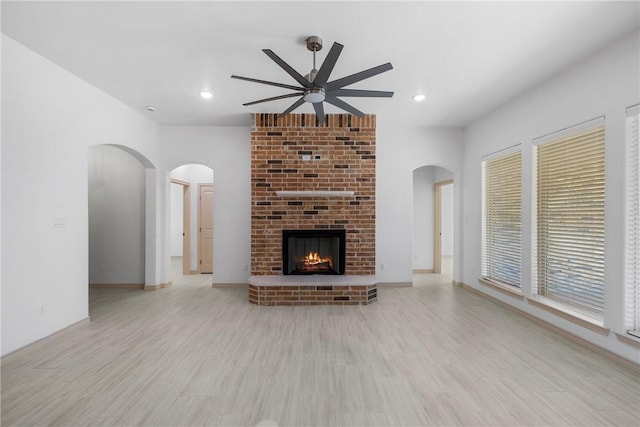 2917 Bombay Ct, Bryan, TX 77808 - unfurnished living room featuring a ceiling fan, light wood-style flooring, a brick fireplace, recessed lighting, and arched walkways