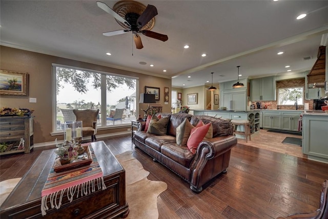 living room featuring ceiling fan, plenty of natural light, dark wood-type flooring, and ornamental molding